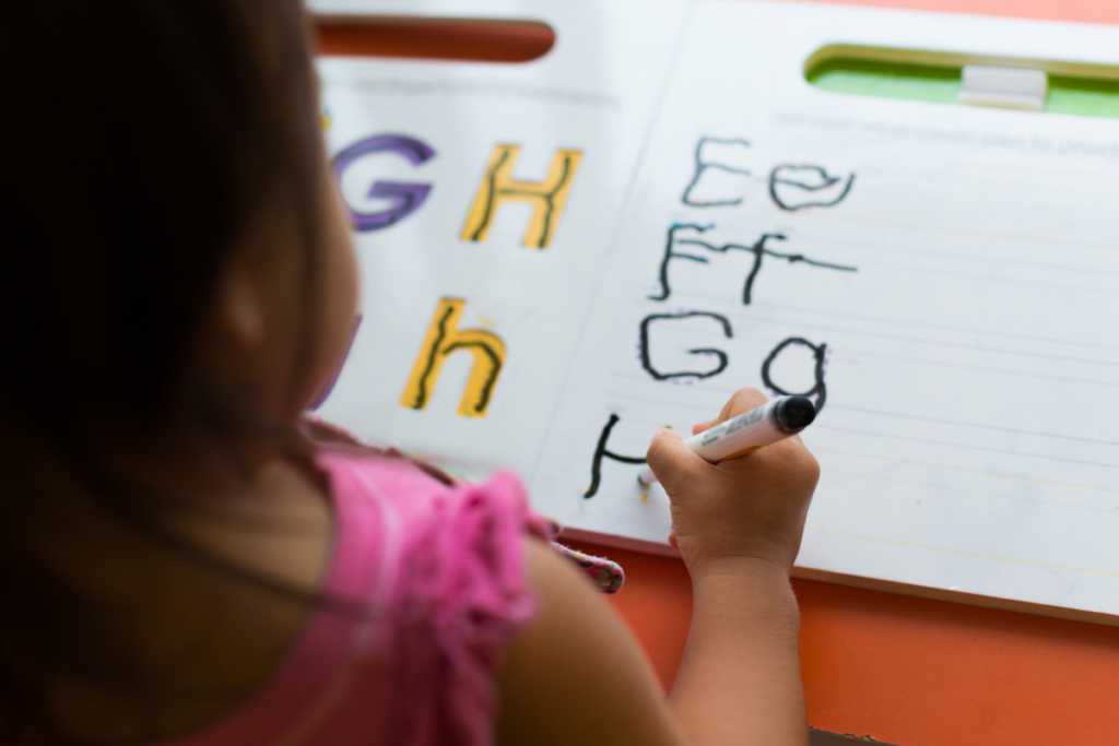 child using dry erase marker for tracing worksheets