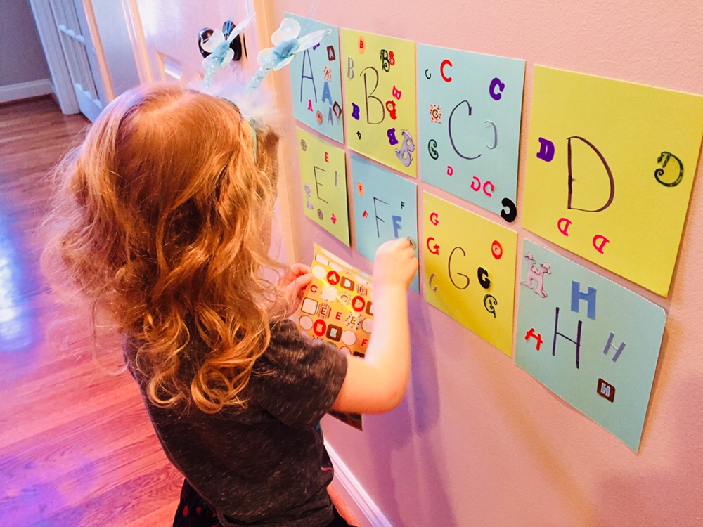 preschool child doing the activity letter sticker match