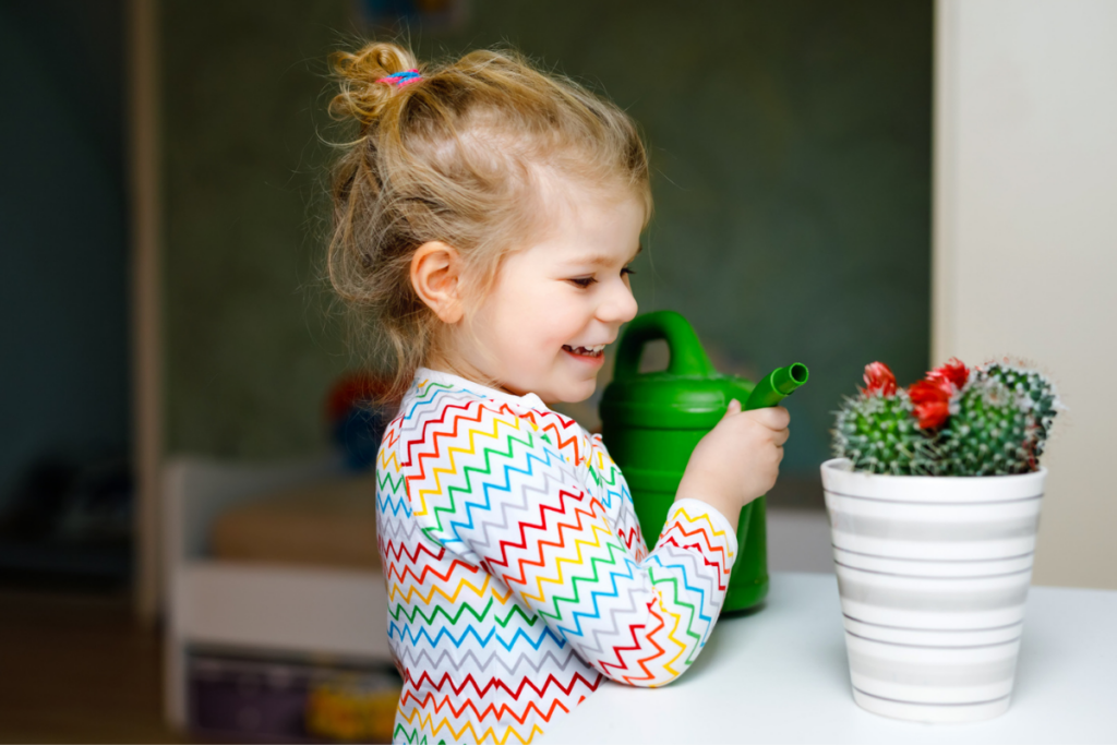 preschool girl watering plant in the spring