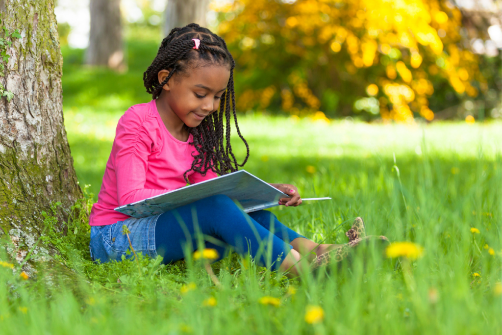 preschool child reading outside in the Spring