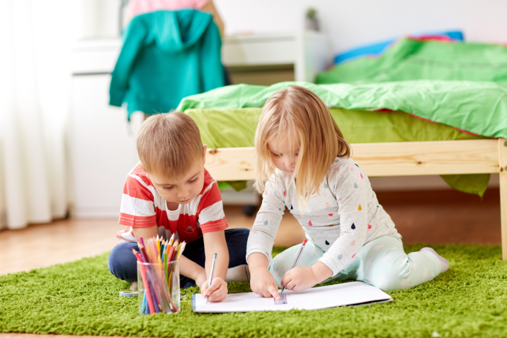 two preschool children writing together on the floor